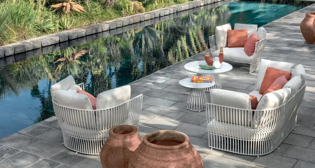outdoor decor with fabiia's exquisite lounge chairs and coffee tables besides pool.
